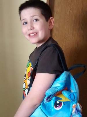 The young boy proudly shows off his pony-themed backpack