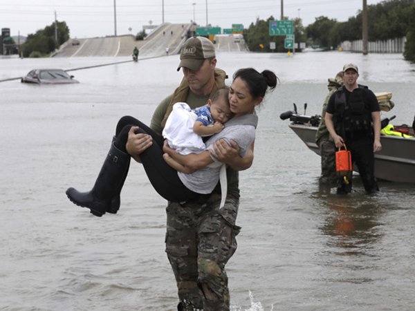 Houston Police officer Daryl Hudeck carries Catherine Pham and her 13-month-old son, Aiden, after rescuing them from their home surrounded by floodwaters on Sunday in Houston.