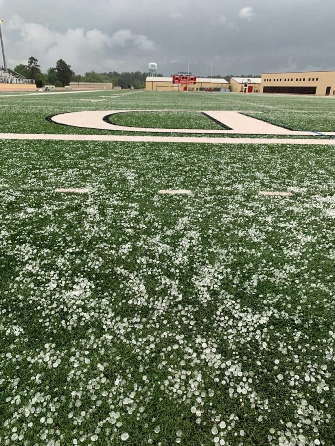 Hail falls across the football field, forcing a delay in the Powder Puff game.