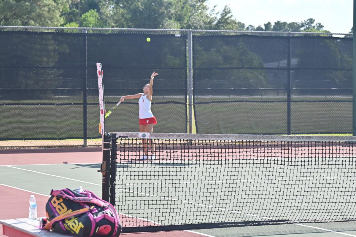 Tomball girl's single starting her match by serving.